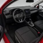 Вид интерьера красного Renault Clio 2023 года, показаны передние пассажирское и водительское сиденья, руль и центральная консоль
