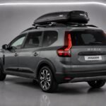 Heckansicht eines grauen Dacia Jogger mit Dachbox in einer Studioaufnahme
