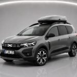 Grauer Dacia Jogger A/T mit Dachbox in einer Studioaufnahme