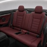 Interior view of 2023 BMW 4.30i Cabrio showing burgundy leather rear seats and seat belts