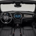 2023 Mini Cooper Cabrio'nun açık tavanlı siyah iç mekan direksiyon ve kontrol paneli