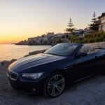 Boğazkent Convertible Rental: BMW Cabrio at Sunset Navy blue BMW convertible parked beside the sea at sunset